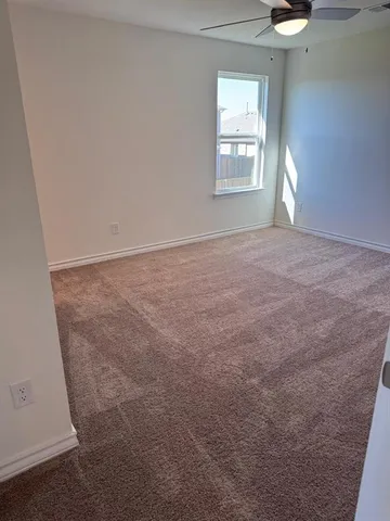 an empty room with windows and chandelier fan