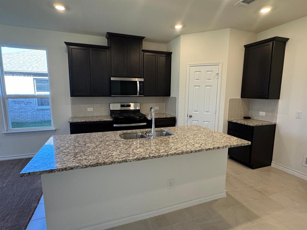 764 Windsor Drive Princeton, TX 75407 - Photo 4 of 18 a kitchen with kitchen island granite countertop counter top space cabinets and stainless steel appliances