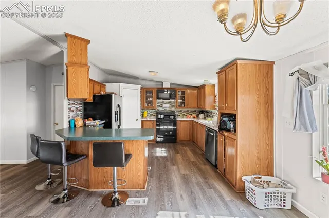 a kitchen with kitchen island stainless steel appliances a stove a refrigerator a sink a dining table and chairs with wooden floor