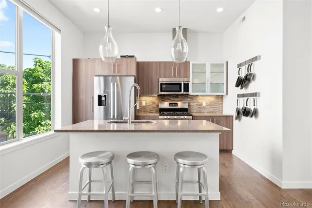 a kitchen with stainless steel appliances a dining table chairs refrigerator and microwave