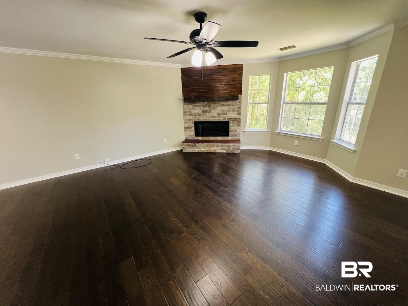 266 Ridgewood Drive Daphne, AL 36526 - Photo 5 of 34 Living space featuring dark wood-finish flooring, a stone and brick fireplace, a ceiling fan with integrated lighting, a bay window with three distinct panes, and crown molding