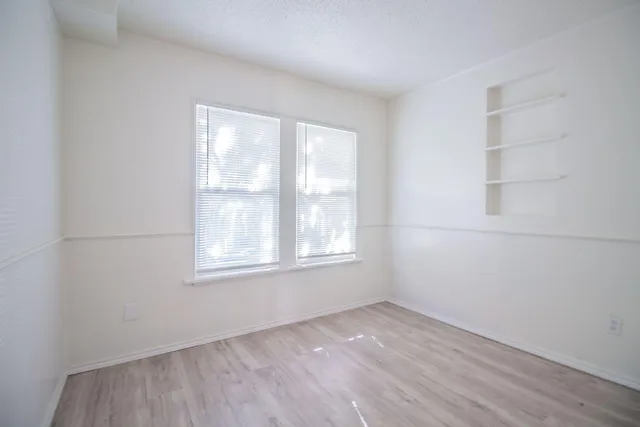 a view of an empty room with a window and wooden floor