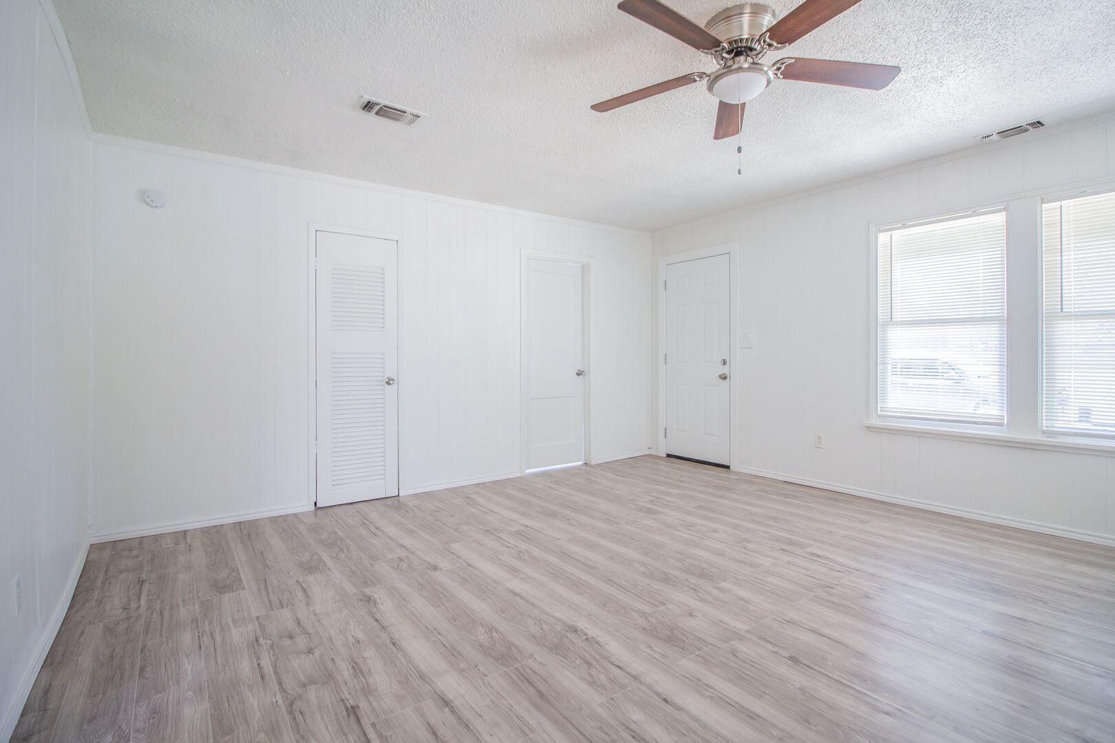 1918 20th Street Lubbock, TX 79411 - Photo 2 of 13 an empty room with wooden floor fan and windows