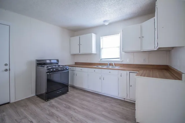 a kitchen with granite countertop a sink cabinets and wooden floor