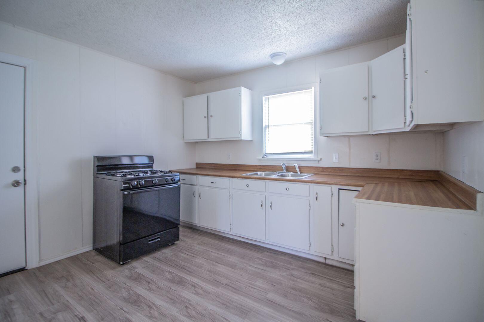 1918 20th Street Lubbock, TX 79411 - Photo 3 of 13 a kitchen with granite countertop a sink cabinets and wooden floor