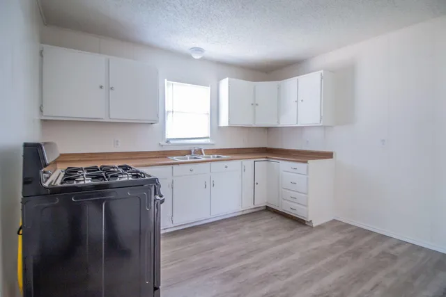a kitchen with a stove sink and cabinets