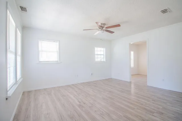 a view of empty room with wooden floor and fan