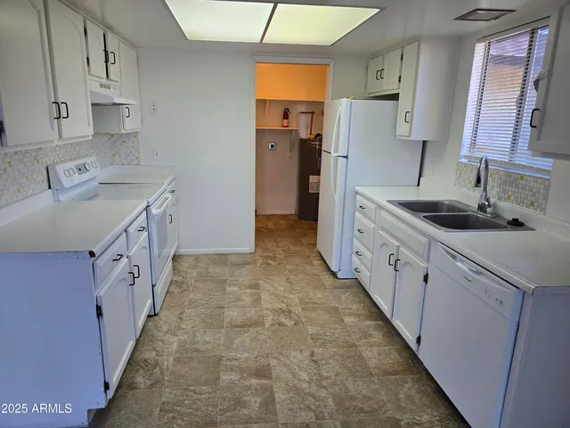 a kitchen with granite countertop a sink stove refrigerator and cabinets