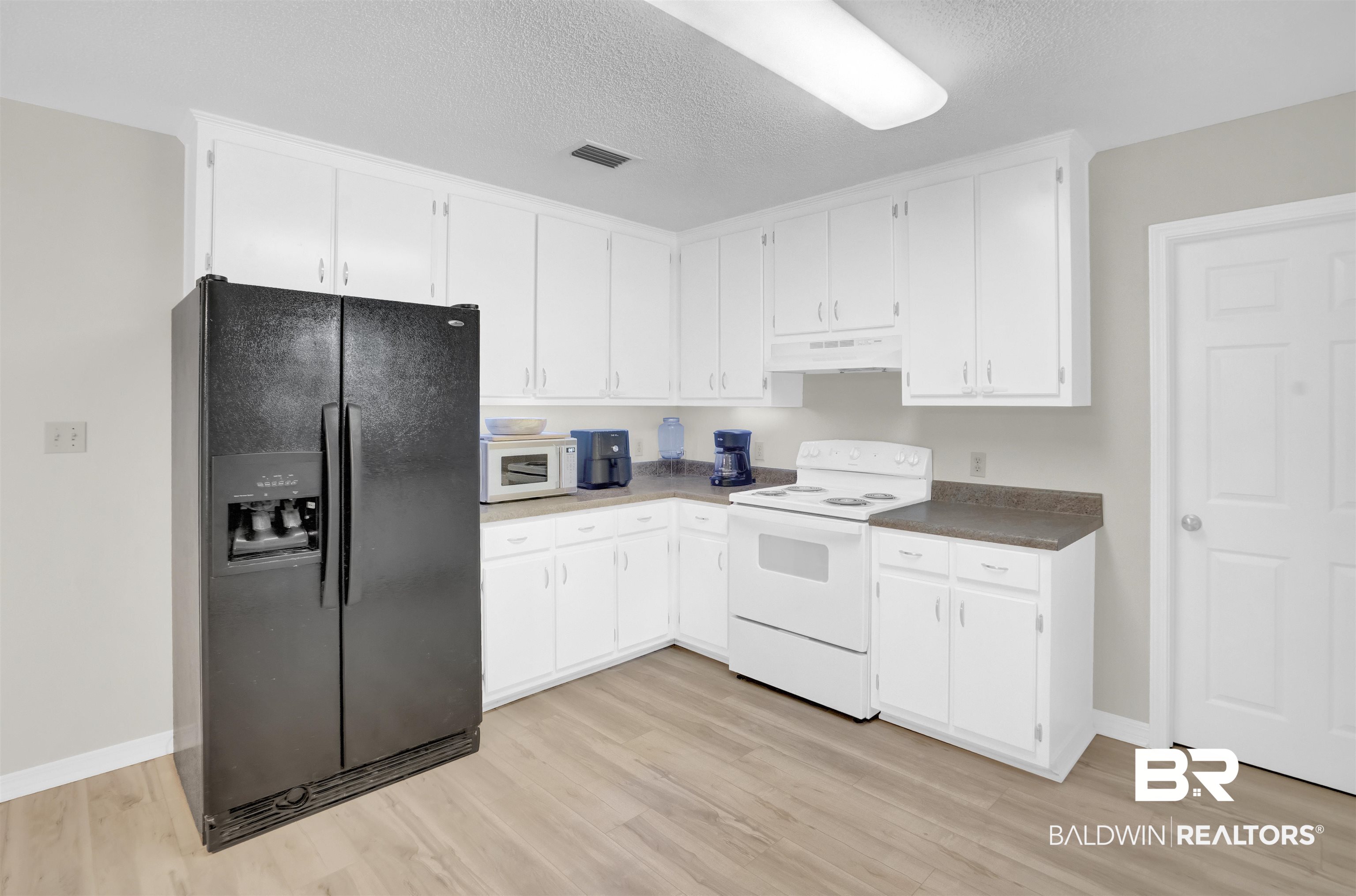 30871 Stanton Road Spanish Fort, AL 36527 - Photo 12 of 35 Kitchen featuring white cabinets, a textured ceiling, light hardwood / wood-style floors, and white appliances