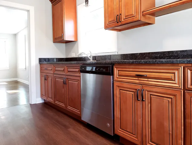 a kitchen with granite countertop wooden cabinets and a wooden floor