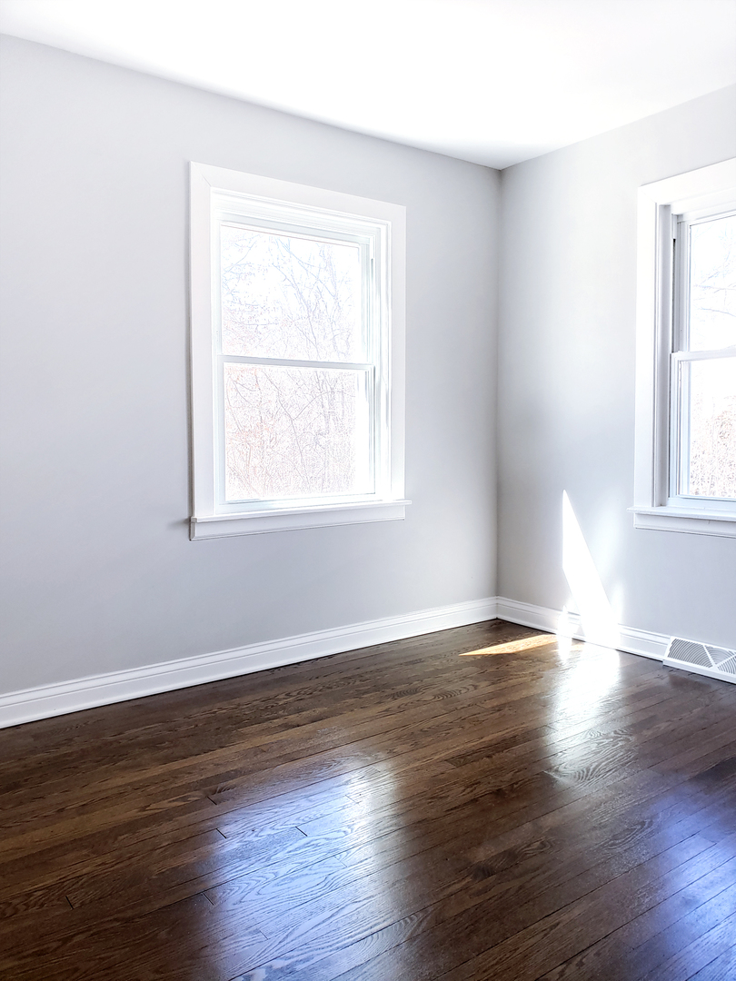 18244 Stewart Avenue Homewood, IL 60430 - Photo 9 of 16 an empty room with wooden floor and windows