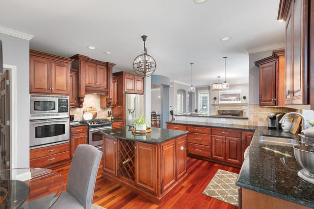 1731 Elyse Lane Naperville, IL 60565 - Photo 11 of 34 a kitchen with stainless steel appliances granite countertop a stove top oven a sink dishwasher a dining table and chairs with wooden floor