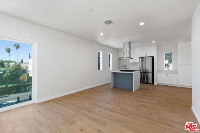 a view of kitchen with kitchen island wooden floor center island and stainless steel appliances