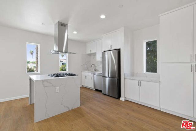 a kitchen with stainless steel appliances a refrigerator a sink a stove a microwave and island