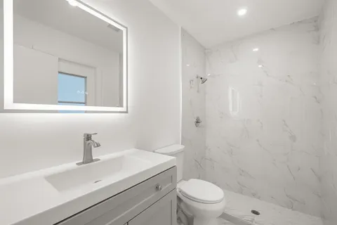 a bathroom with a sink a toilet a shower and a mirror