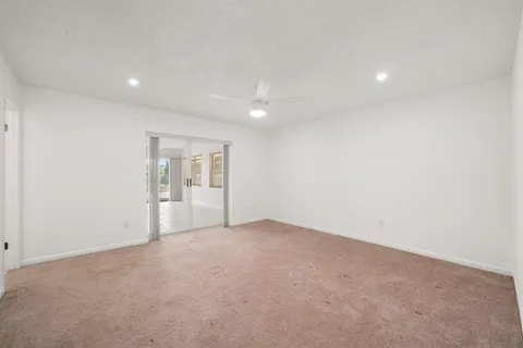 a view of an empty room with wooden floor and kitchen