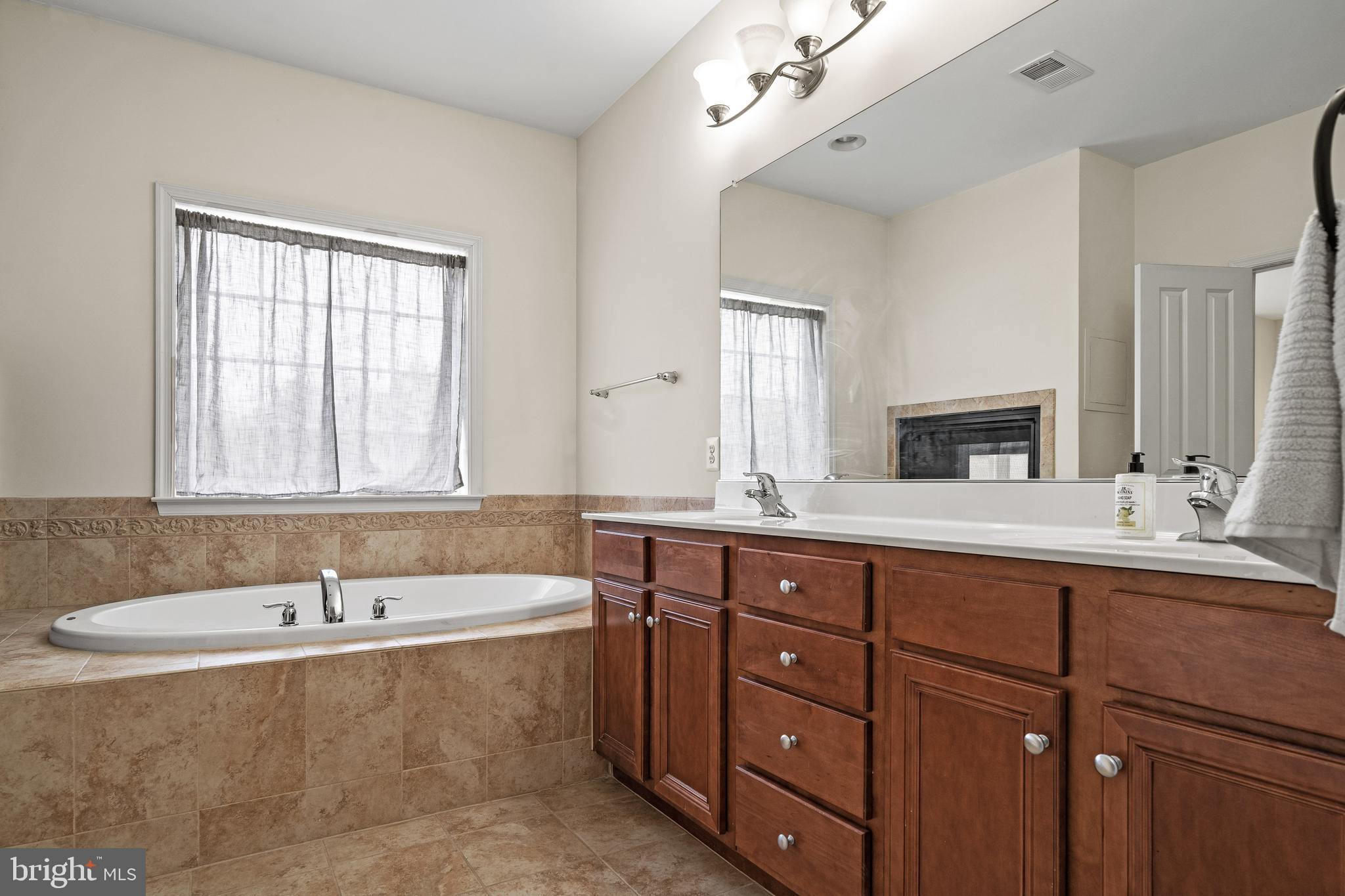 8722 Polished Pebble Way Laurel, MD 20723 - Photo 23 of 58 a bathroom with a tub sink double vanity and mirror