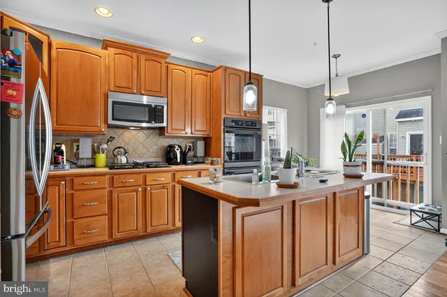 a kitchen with stainless steel appliances a sink a stove a refrigerator cabinets and a window