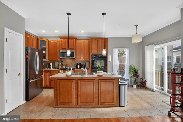 a kitchen with stainless steel appliances granite countertop a refrigerator a sink dishwasher a stove and a dining table with wooden floor