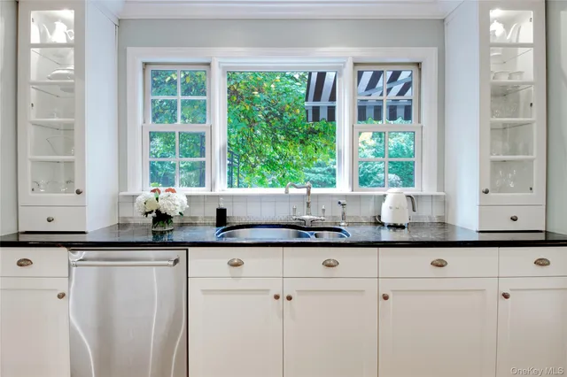 a kitchen with granite countertop a sink and white cabinets