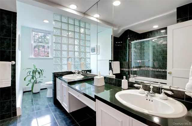 a bathroom with a granite countertop sink a toilet and shower