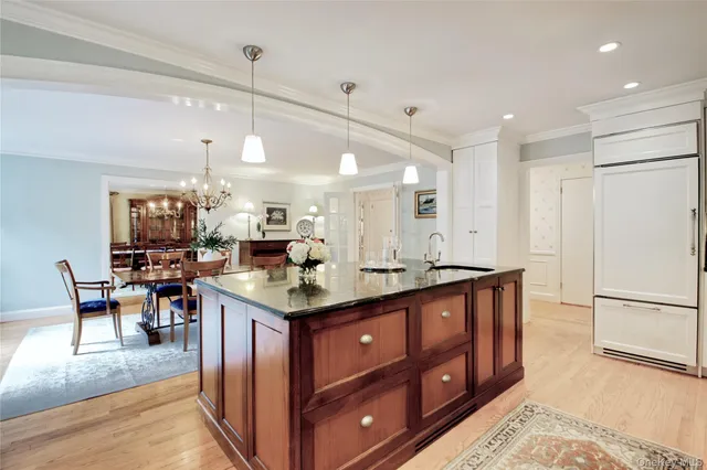 a kitchen with stainless steel appliances granite countertop a stove refrigerator a dining table and chairs with wooden floor