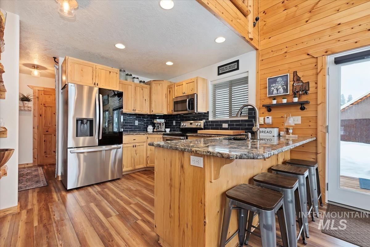 3 Boone Road Garden Valley, ID 83622 - Photo 9 of 49 Kitchen featuring stainless steel appliances, granite countertops, wood-finish flooring, and natural wood paneling