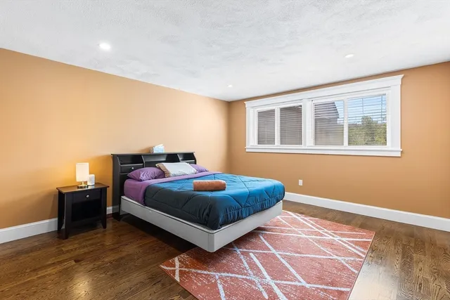 a bedroom with a bed lamp on desk and a window