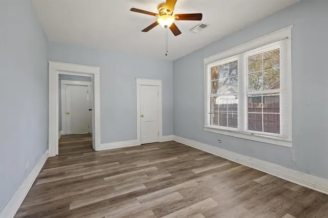 a view of empty room with wooden floor and fan