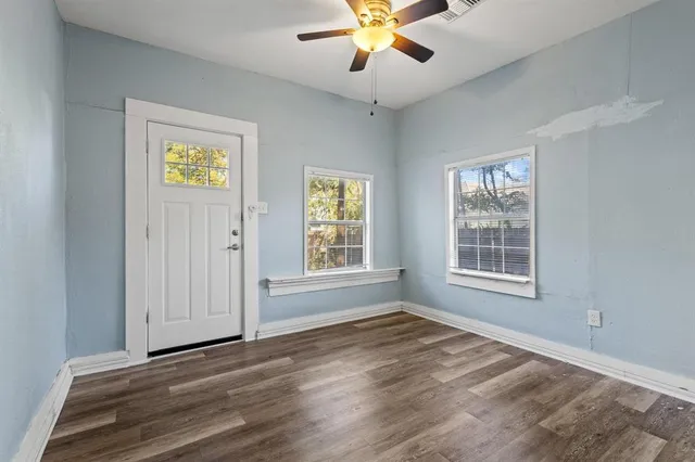 a view of an empty room with a window and wooden floor