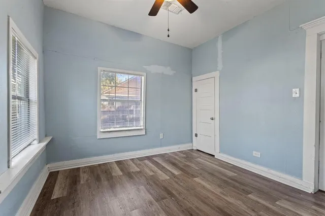 a view of an empty room with a window and wooden floor