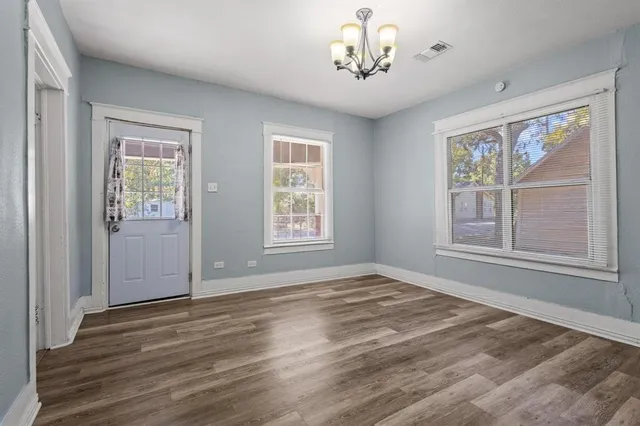 a view of an empty room with a window and wooden floor