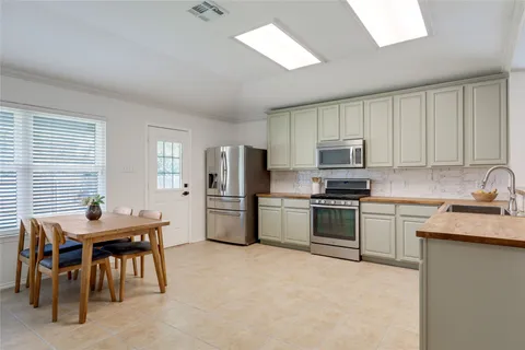 a kitchen with stainless steel appliances granite countertop a stove top oven a sink a dining table and chairs