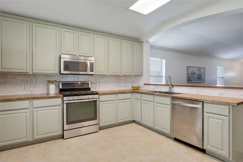 a kitchen with cabinets appliances a sink and a window