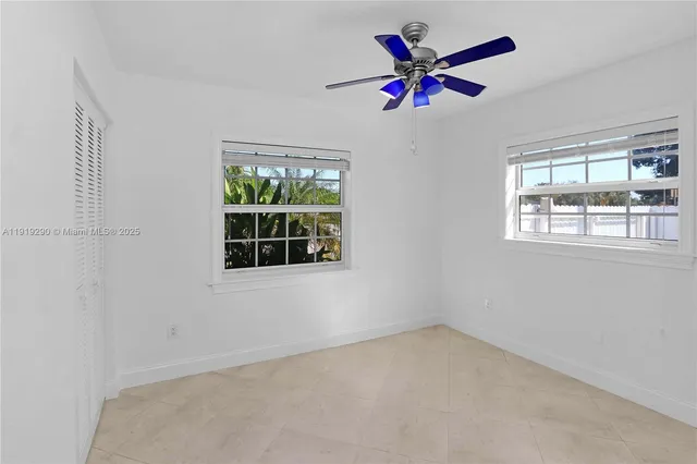an empty room with ceiling fan and window