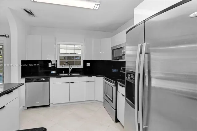 a kitchen with stainless steel appliances granite countertop a refrigerator sink and stove