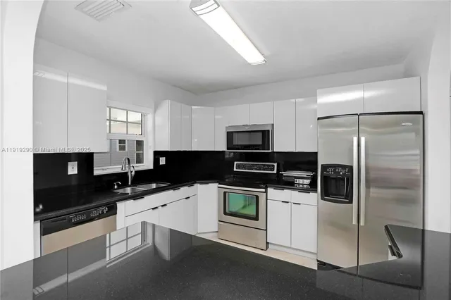 a kitchen with a sink stainless steel appliances and white cabinets