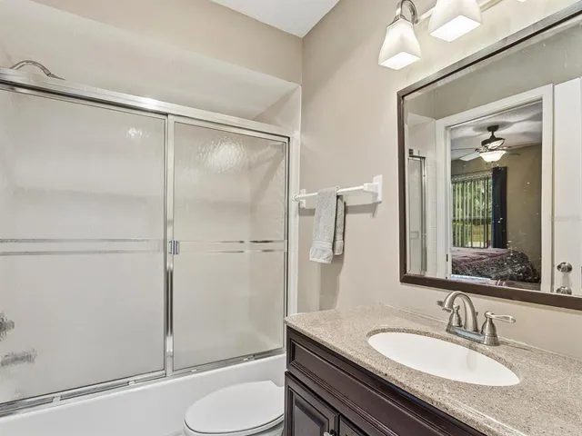 a bathroom with a granite countertop sink toilet and shower