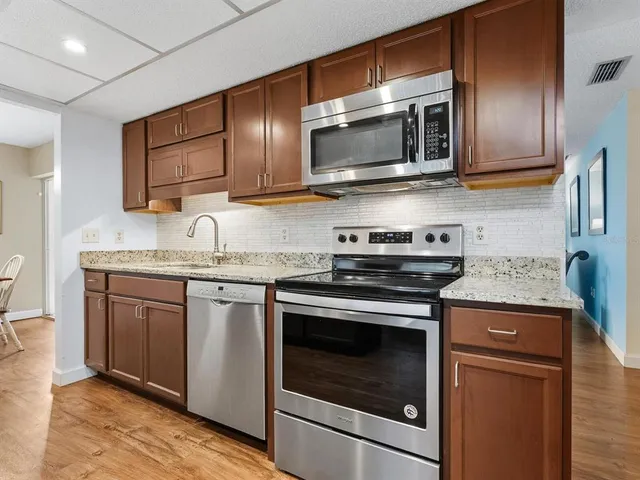 a kitchen with stainless steel appliances granite countertop a stove microwave and sink