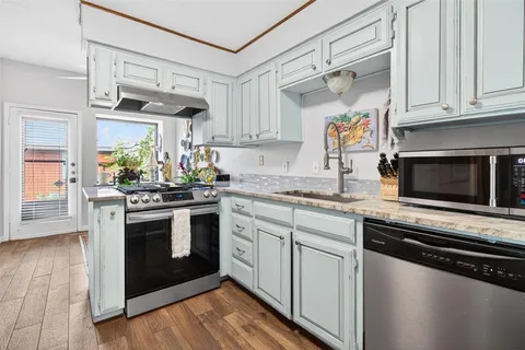 a kitchen with stainless steel appliances granite countertop a stove a sink and a microwave