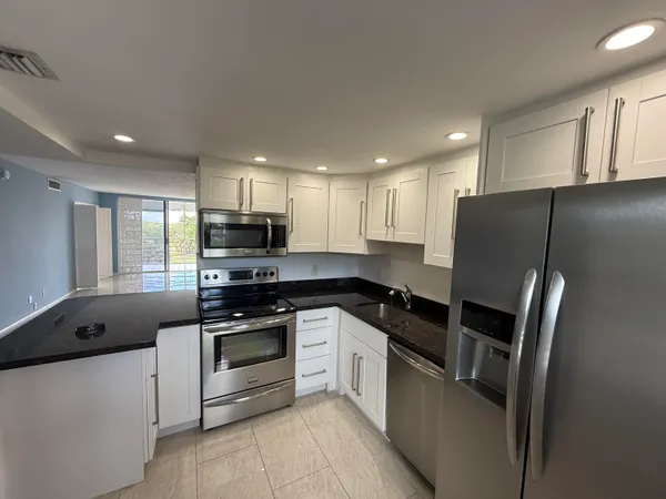 a kitchen with granite countertop a refrigerator stove microwave and sink