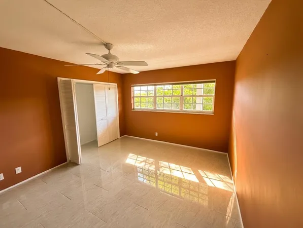 an empty room with windows and fan