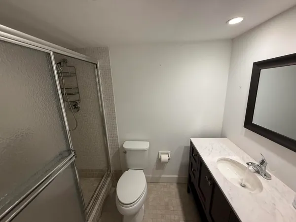 a bathroom with a granite countertop toilet sink and mirror
