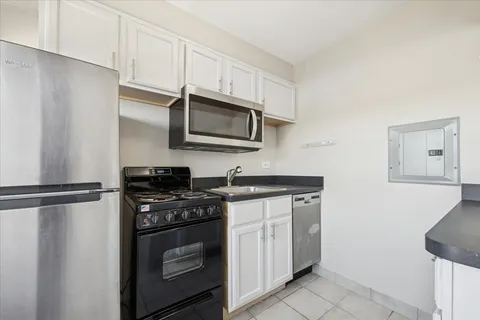 a kitchen with stainless steel appliances white cabinets and a stove top oven