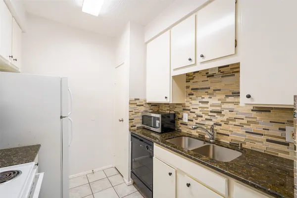 a kitchen with granite countertop a sink stove and cabinets