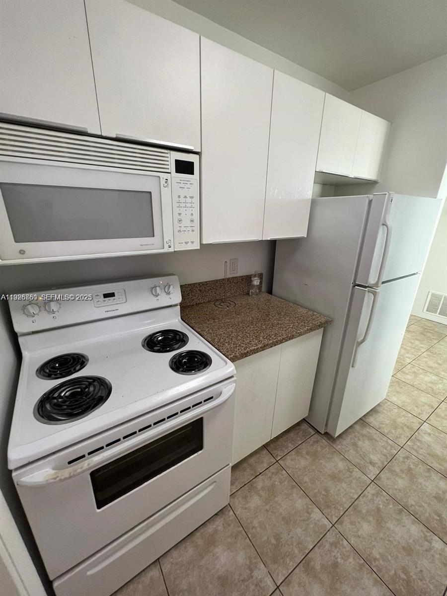 105 Northeast 12th Avenue, Unit 17 Hallandale Beach, FL 33009 - Photo 8 of 11 a kitchen with a stove and white cabinets