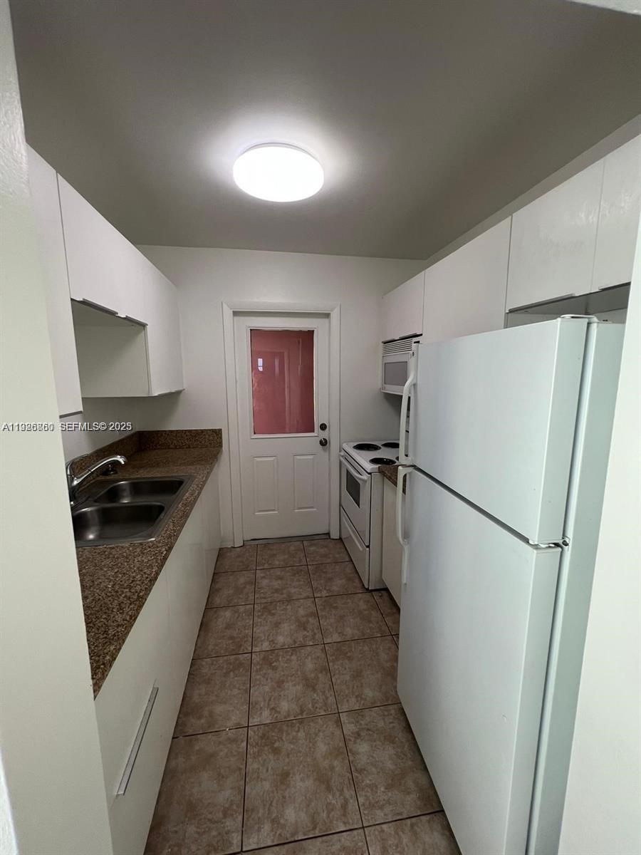 105 Northeast 12th Avenue, Unit 17 Hallandale Beach, FL 33009 - Photo 9 of 11 a kitchen with a refrigerator sink stove and cabinets