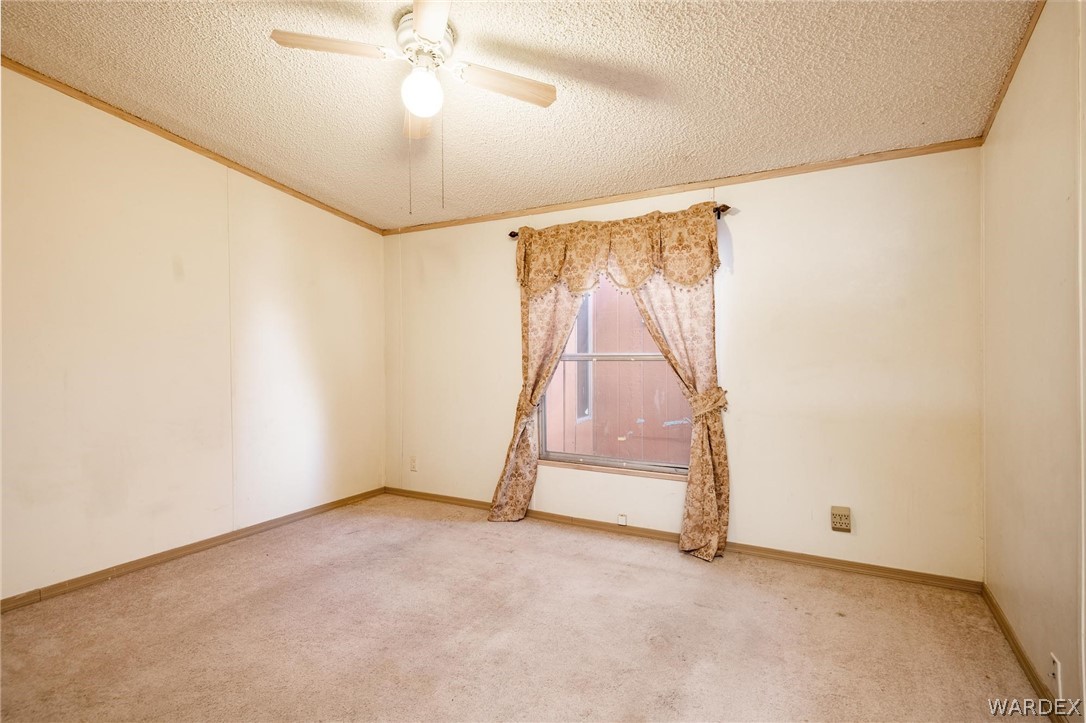 4496 Cowlic Road Golden Valley, AZ 86413 - Photo 22 of 50 an empty room with a ceiling fan and carpet