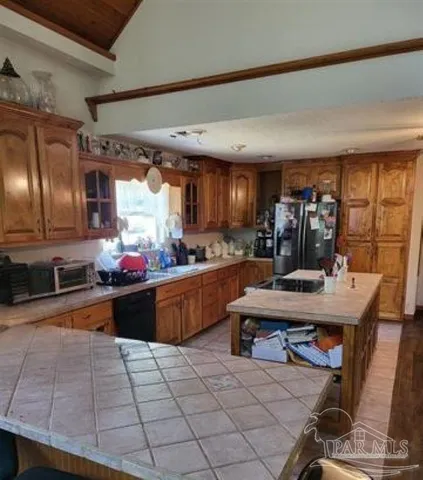 a kitchen with stainless steel appliances kitchen island granite countertop a table chairs and a refrigerator