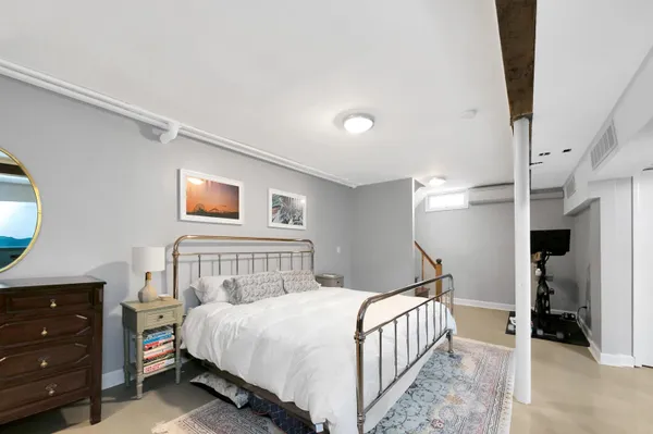 a bedroom with a bed and a lamp on dresser